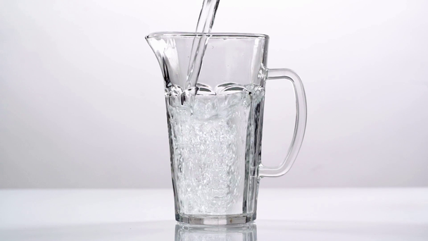 studio pousse de l'eau versant dans une cruche en verre transparent sur fond blanc
 - Séquence, vidéo