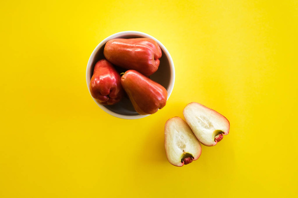 Syzygium Aqueum, φρούτα Bell ή Jambu αέρα σε Νορβηγικά τοπική γλώσσα, είναι ένα φρούτο που έχει ένα σχήμα, όπως ένα κουδούνι; γυρίστηκε σε απομονωμένες κίτρινο φόντο. - Φωτογραφία, εικόνα