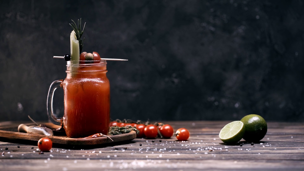 salt falling in red cocktail in glass jar decorated with vegetables on skewer - Imágenes, Vídeo