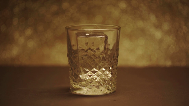 slow motion shoot of big ice cube dropping into textured glass - Metraje, vídeo