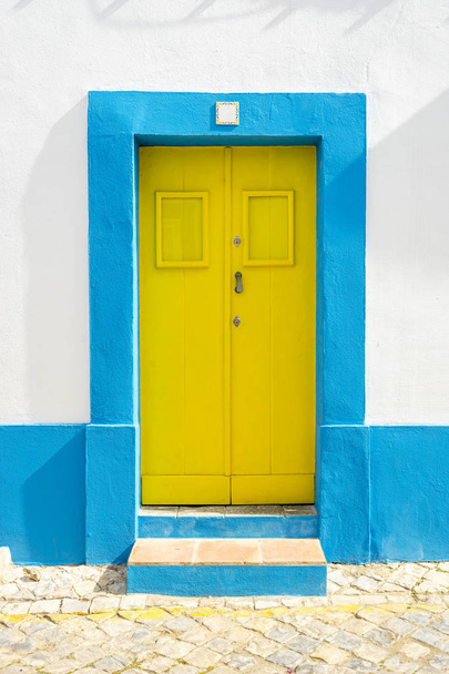 Yellow door in traditional portuguese house painted on blue and  - Photo, Image