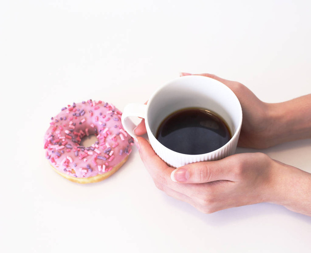 Womans hands holding cup of coffee and donut on the wooden table. With copy space.Top wiev. Spring design. Feminine styled stock photo. - Zdjęcie, obraz