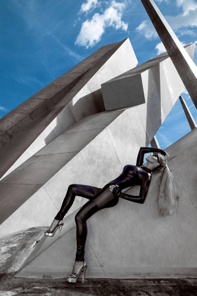 Retrato de alta moda de mujer joven elegante al aire libre. Modelo con mono sexy negro, gafas de sol de ojo de gato, fondo de pared gris - Imagen
 - Foto, imagen