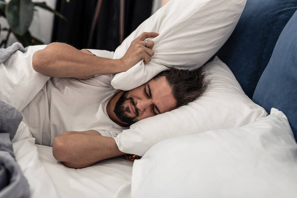 Unhappy sad man wanting to stay in bed longer - Photo, image