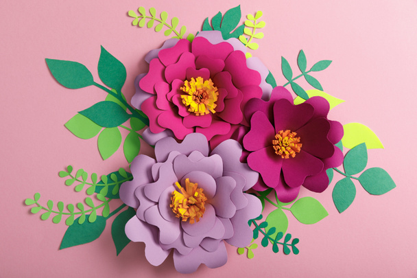 το top view από χαρτί, πολύχρωμα λουλούδια και πράσινα φύλλα σε ροζ φόντο  - Φωτογραφία, εικόνα