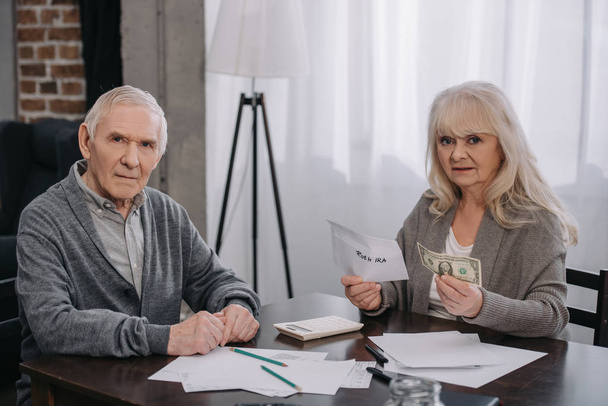 couple âgé tenant de l'argent, enveloppe avec lettrage 'roth ira' et regardant la caméra
 - Photo, image