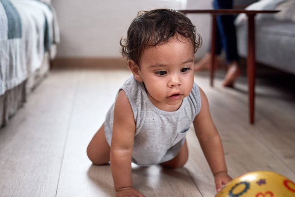 Cute mixed race baby boy crawling after a ball on floor  - Zdjęcie, obraz