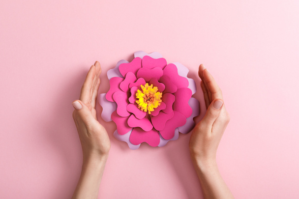 cropped view of woman with paper flower on pink background - Fotó, kép