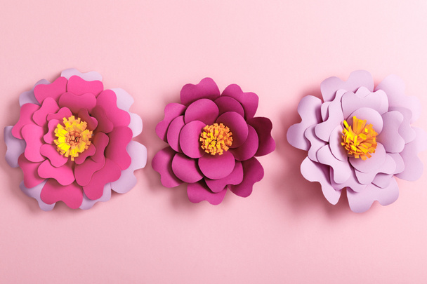 top view of multicolored paper flowers on pink background - Foto, Bild