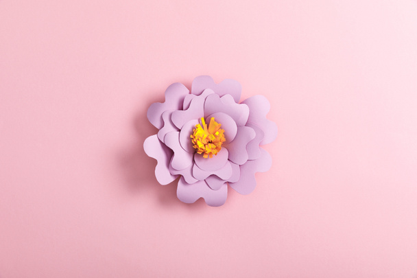 bovenaanzicht van lila papier bloem op roze achtergrond - Foto, afbeelding