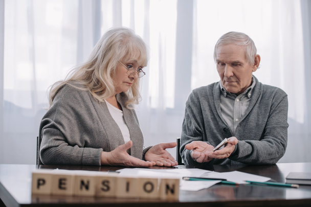 pareja de ancianos en la mesa con la palabra 'pensión' hecha de bloques de madera en primer plano
 - Foto, Imagen