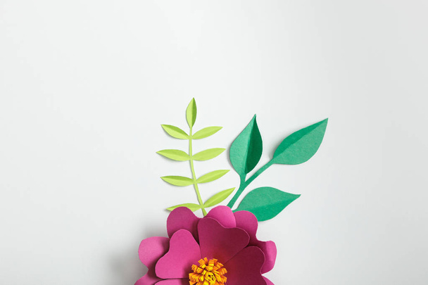 top view of pink paper flower and green plants on grey background - Fotografie, Obrázek