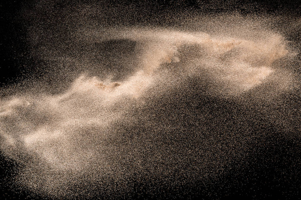 Abstract sand cloud. Golden colored sand splash against black background. - Photo, Image