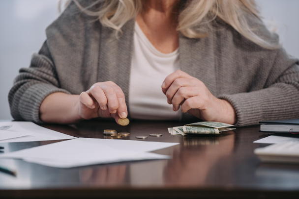 περικοπεί άποψη της γυναικείας συνταξιούχος κάθεται στο τραπέζι και μετρώντας τα χρήματα στο σπίτι - Φωτογραφία, εικόνα