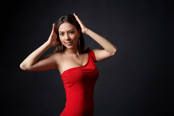 Beautiful woman in red dress supporting something imaginary on her head - Foto, imagen