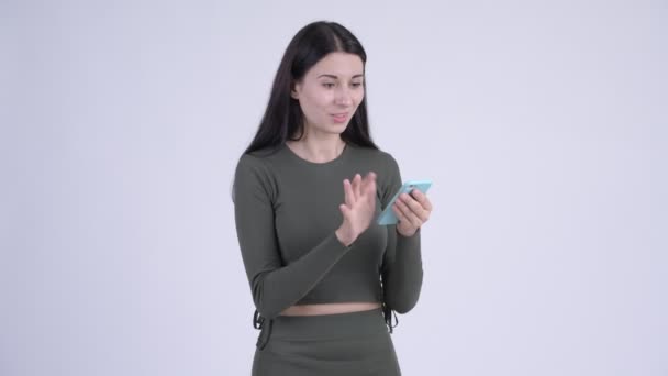 Happy young beautiful woman using phone and looking surprised - Metraje, vídeo