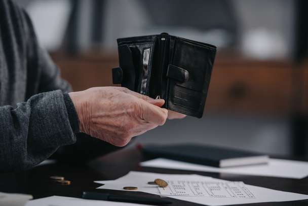 selective focus of male pensioner sitting at table with paperwork and counting money - Foto, imagen