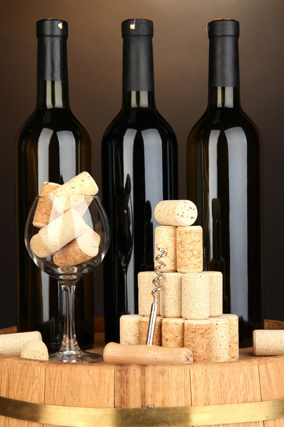 Wine and corks on barrel on brown background - Фото, зображення