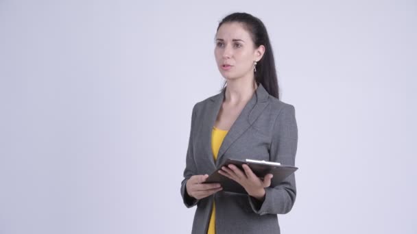 Young beautiful businesswoman talking while holding clipboard - Video, Çekim
