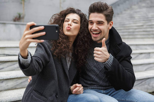 Image of excited couple man and woman 20s in warm clothes, takin - Photo, Image