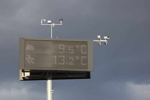 Tablica informacyjna elektroniczny pomiar temperatury na tle burzowe. Kamery i czujniki pogody. Infrastruktury pomocy dla kierowców na autostradzie. Ostrzeżenie Pogoda - Zdjęcie, obraz