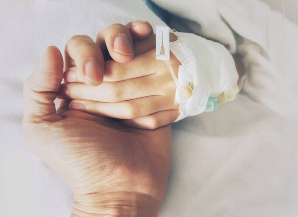 Χέρι-χέρι, οι γονείς, κρατώντας το χέρι ένα παιδί τυλιγμένο με γάζες για υποστήριξη στο νοσοκομείο. - Φωτογραφία, εικόνα