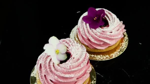 gładkie panorama w dół na dwa różowe zephyr ciasteczka ozdobione kwiaty fioletowe i białe serwowane na czarny - Materiał filmowy, wideo