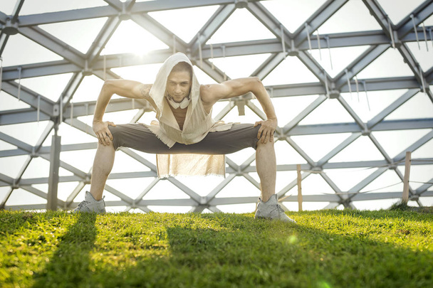 Attractive athletic man practicing yoga and warming up outdoors - Foto, afbeelding