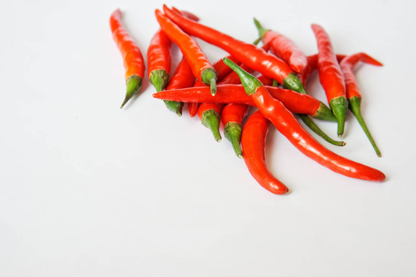 Pods of red hot chili pepper lie on a white surface. Free space for inscriptions.  - Photo, Image