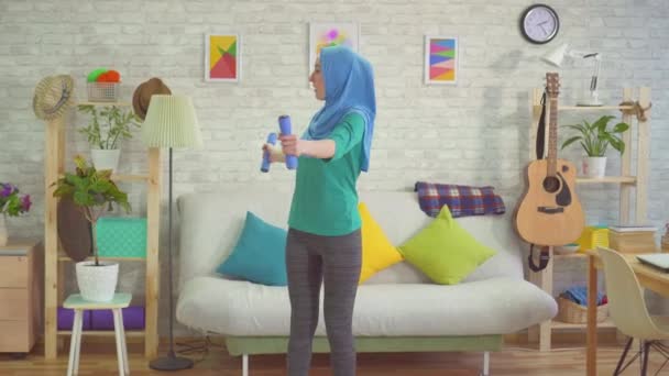 Sporty muslim woman in hijab engaged with dumbbells at home - 映像、動画