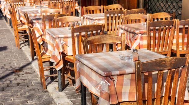 Taverne grecque extérieure, tables et chaises vides, journée ensoleillée, centre-ville
 - Photo, image