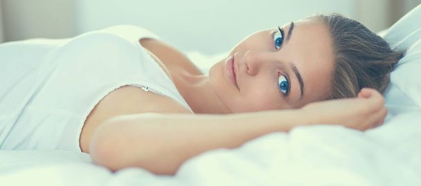 Beautiful young woman lying in bed comfortably and blissfully - Фото, зображення