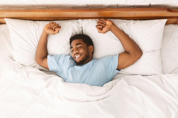 junger afrikanisch-amerikanischer Mann schläft im Bett Draufsicht - Foto, Bild