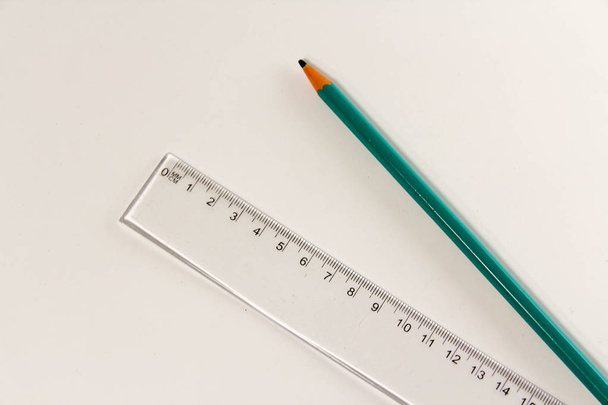 Пластикова лінійка та дерев'яний олівець на білому
 - Фото, зображення