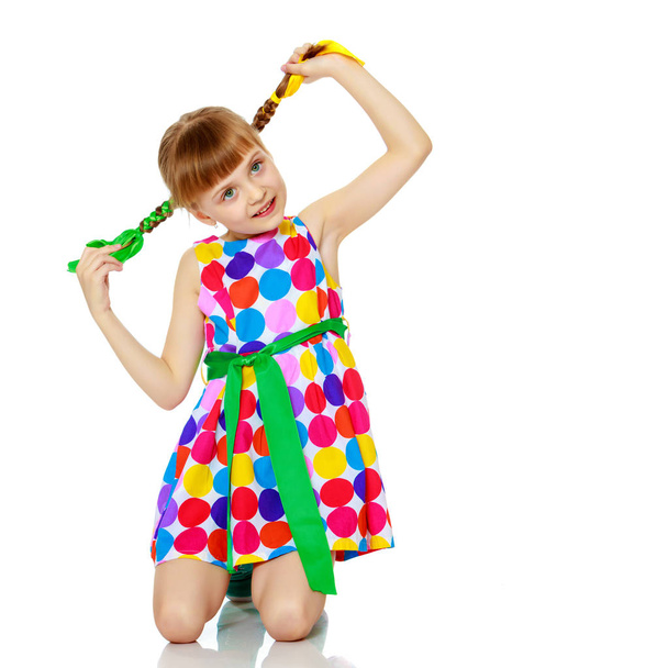 A little girl in a dress with a pattern from multi-colored circl - Fotó, kép