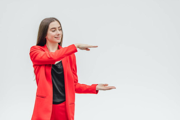 Portrait of a beautiful young brunette. During this, the girl raised two hands. Showing the plane with your hands. Dressed in a red jacket. - Foto, Bild