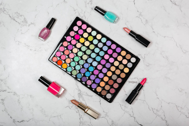 Flat lay of various cosmetic products with colorful eyeshadow palette on natural marble texture - Φωτογραφία, εικόνα