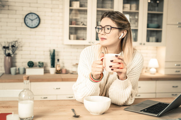 Peaceful good-looking woman in clear glasses holding glass of tea - 写真・画像