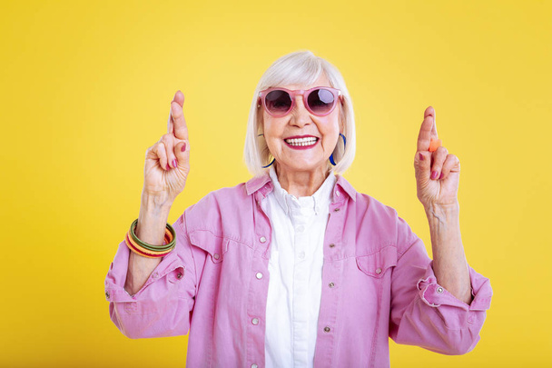 Stylish modern retired woman with bright manicure having fingers crossed - Foto, imagen