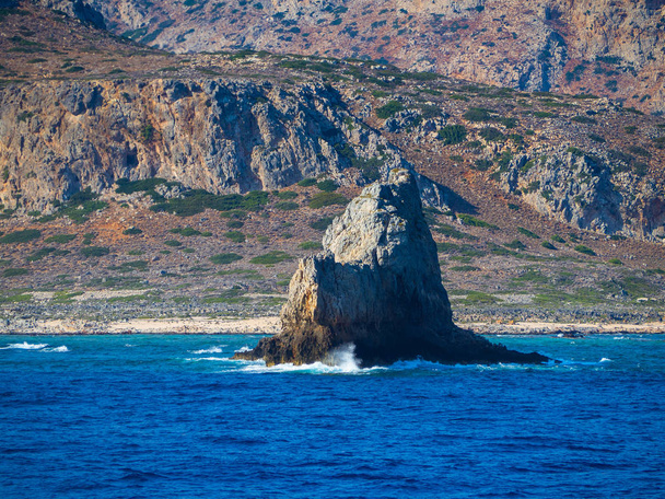Hermosa montaña y costa rocosa con gran formación rocosa que sale del agua
 - Foto, imagen