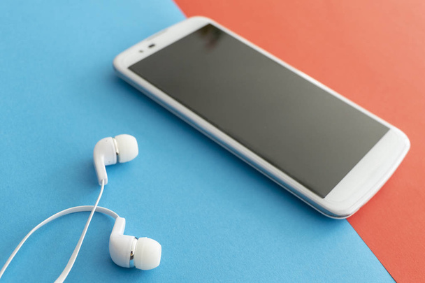 White Innovative Mobile Phone with Headphones isolated on a Blue - Photo, Image