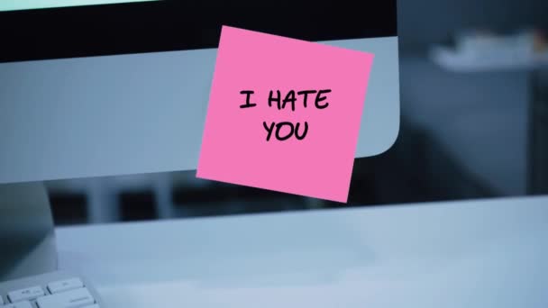 I hate you. The inscription on the sticker on the monitor. Message. Motivation. Reminder. Handwritten text written with a marker. Color sticker. A message for an employee, a colleague - Footage, Video