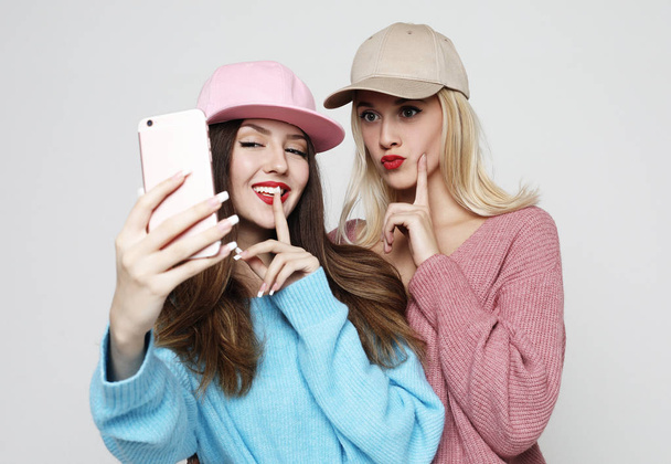 Two teenage girls friends in hipster outfit make selfie on smart phone.  - Photo, Image