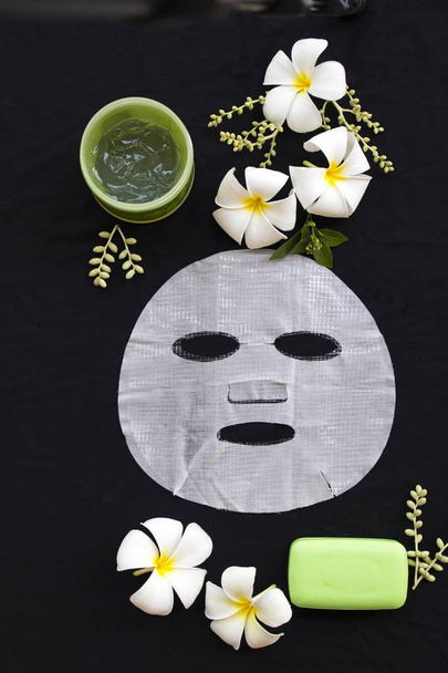 kosmetyki naturalne ziołowe aromat hialuronowy siatki arkusza maska, kojący żel i opieki zdrowotnej mydło do skóry twarzy, wyciąg z kwiatu frangipani essence maseczka na czarnym tle  - Zdjęcie, obraz