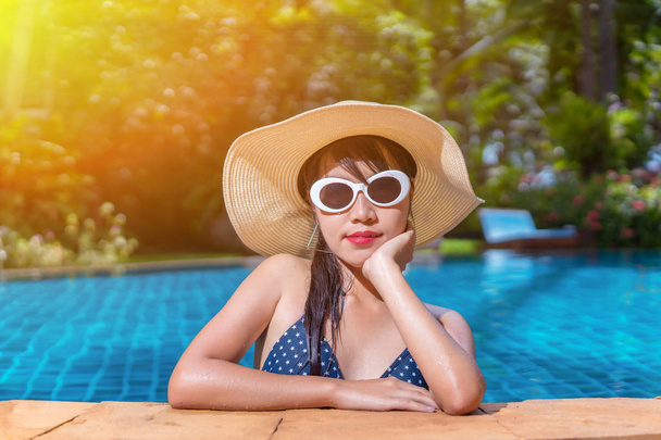 Muotokuva kaunis aasialainen nainen bikinit uima-allas hänen aurinkoa auringolla hattu rentouttava loma nauttia trooppinen kesäkausi uima-altaalla
. - Valokuva, kuva