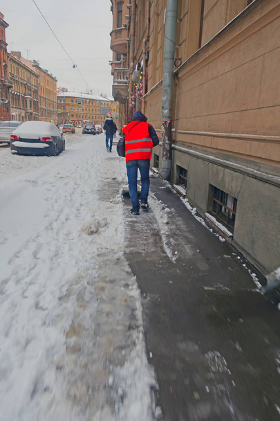 concierge dans un gilet orange, enlever la neige du trottoir après une chute de neige
 - Photo, image