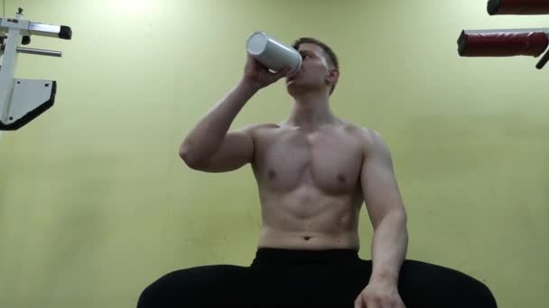 Mladý muž pitné vody v tělocvičně. Ten chlap používá proteinový koktejl - Záběry, video