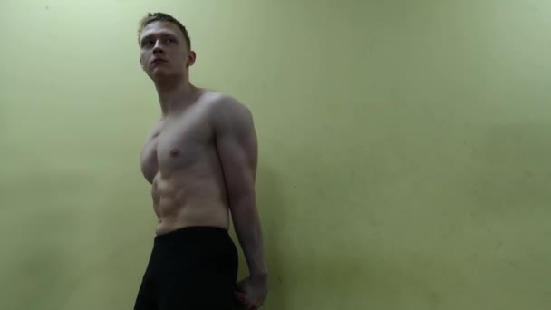 Lekkoatletycznego mężczyzna pozowanie na ścianę w siłowni - Materiał filmowy, wideo