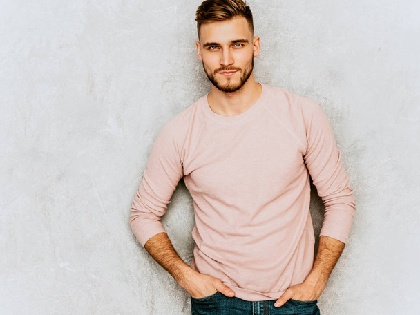 Retrato de guapo serio hipster lumbersexual modelo de hombre de negocios con ropa rosa de verano casual. Moda elegante hombre posando contra la pared gris
 - Foto, Imagen