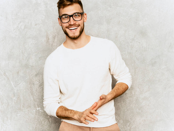 Portrait of handsome smiling hipster lumbersexual businessman model wearing casual summer white clothes and spectacles. Fashion stylish man posing against gray wall - Fotoğraf, Görsel
